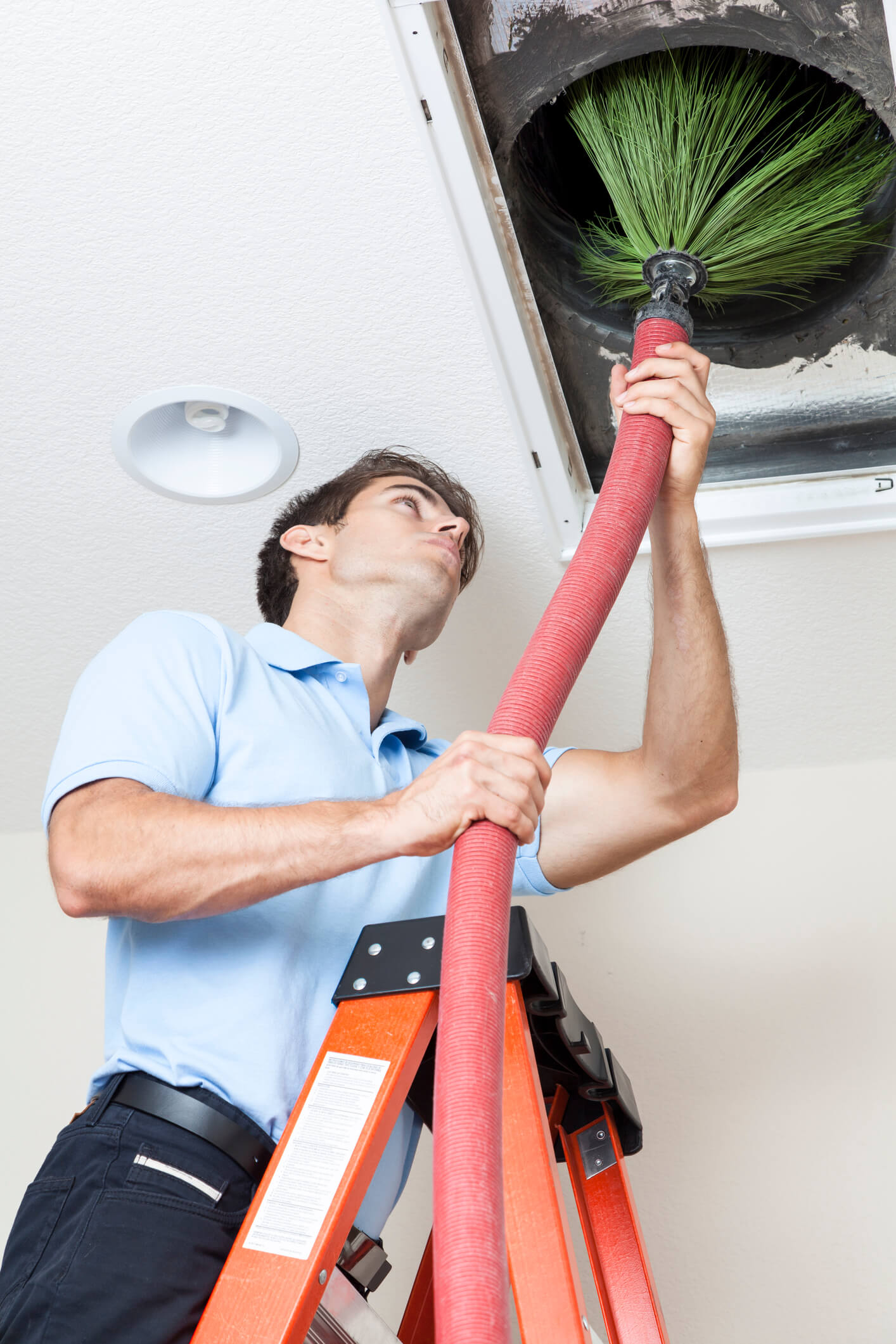 Tech on ladder putting hose and brush into air duct